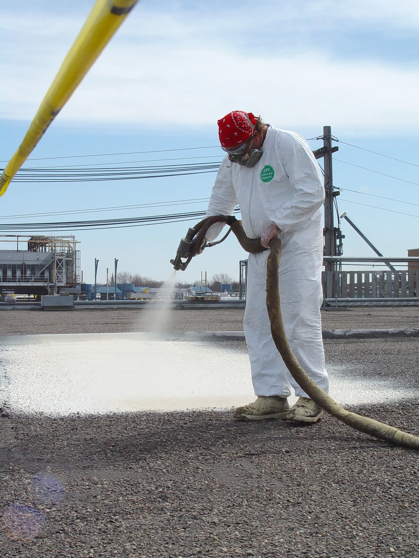 Roofer spray applying a protective roof coating